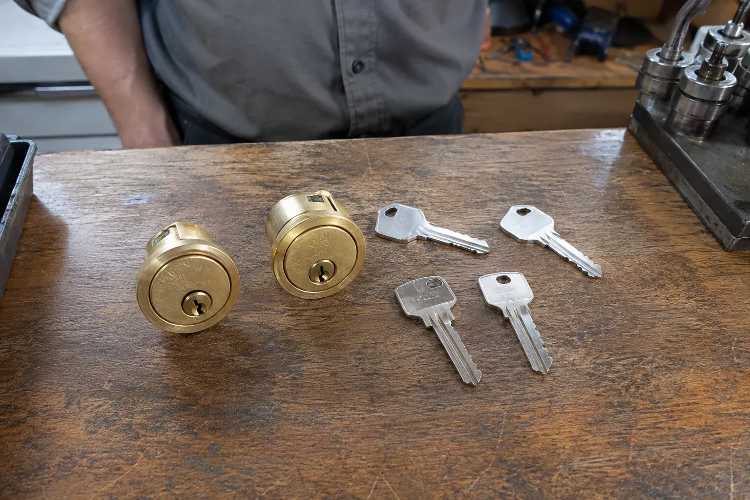 Two detached brass lock cylinders and four house keys on a wooden counter. — Lock Rekeying, Norfolk County